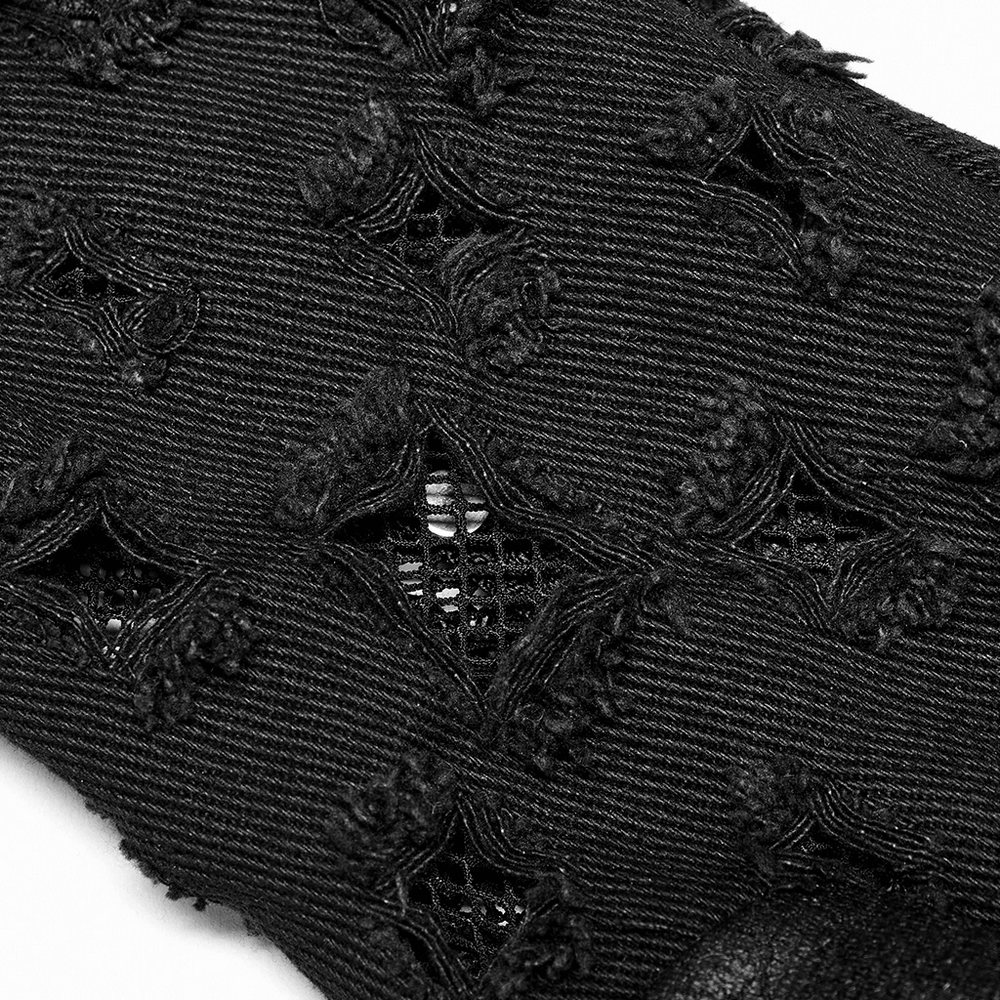 Close-up of distressed black denim with gauze and unique punk detailing for an edgy look.