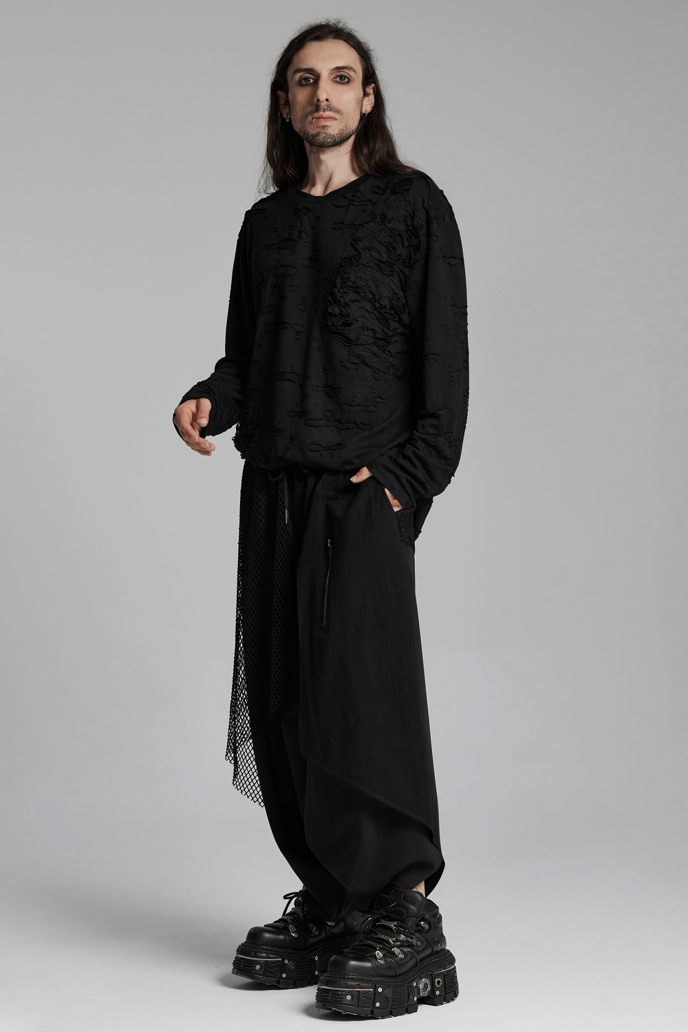 Person wearing a distressed gothic knit top with layered tattered design, showcasing a casual silhouette and rebellious textures.