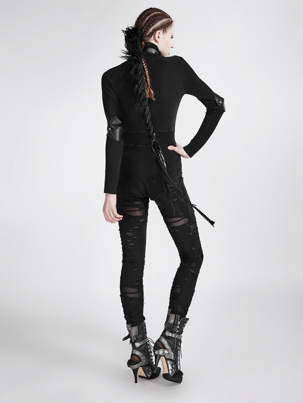 Woman in distressed gothic mesh-panel leggings and sleek black top, showcasing bold punk style and edgy fashion.