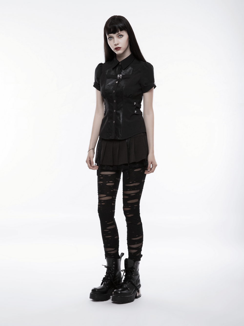 Gothic woman in distressed mesh-panel leggings and black shirt, showcasing punk rave style and bold fashion.