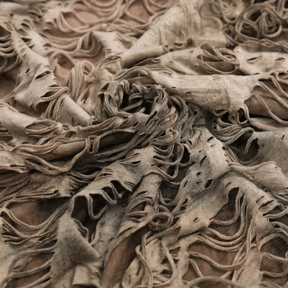 Close-up of shredded fabric showcasing grunge layers for a distressed hooded duster cape in alternative streetwear style.