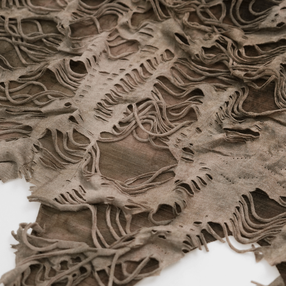 Close-up of distressed fabric with shredded layers, showcasing the grunge texture for alternative streetwear fashion.