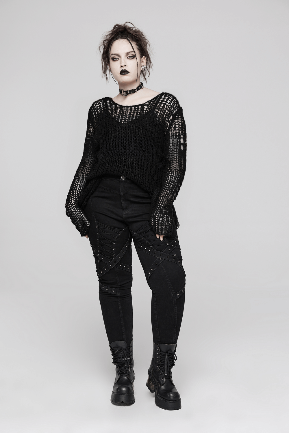 Model wearing a distressed mohair pullover sweater with holes, paired with edgy black pants and combat boots.