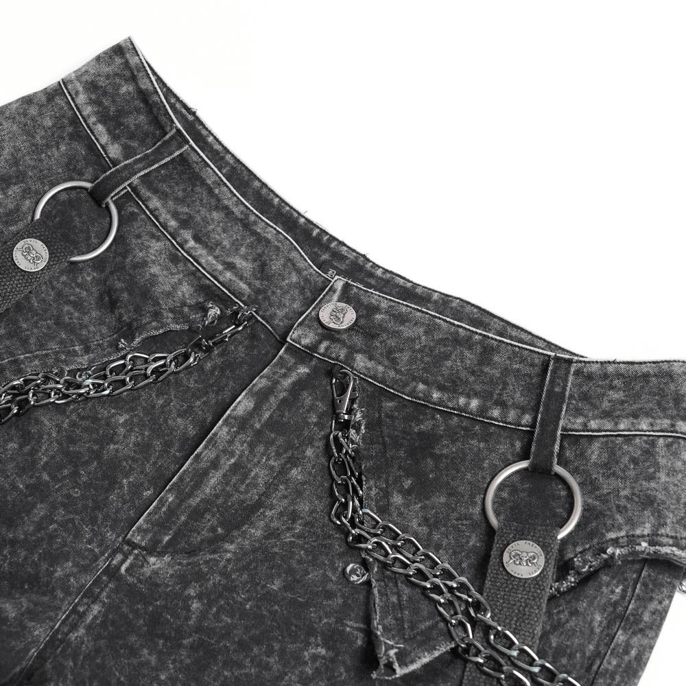 Close-up of distressed black flare pants with chains and buckle straps, showcasing punk fashion details.