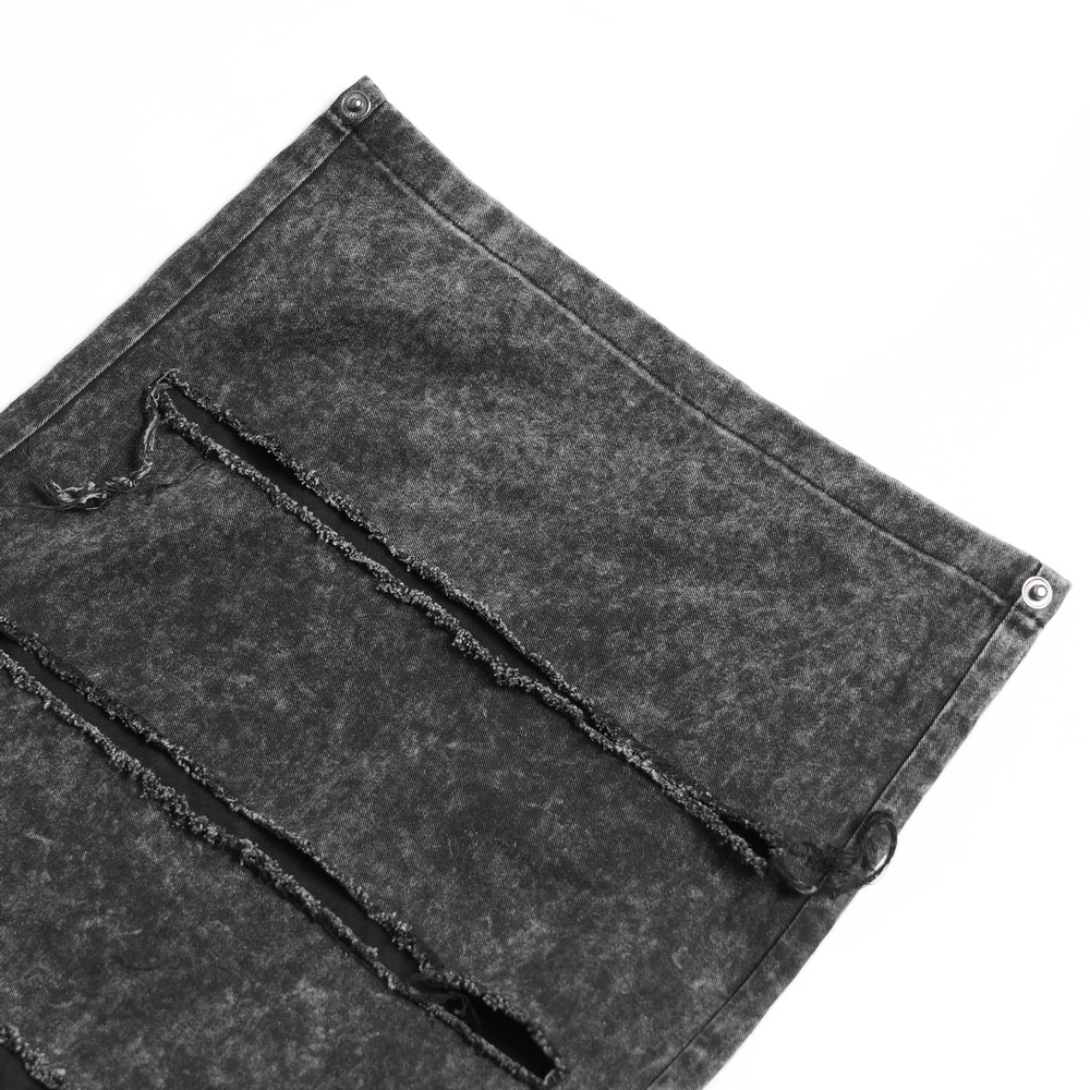 Close-up of distressed black fabric showcasing ripped panels and metal buttons for punk flare pants.