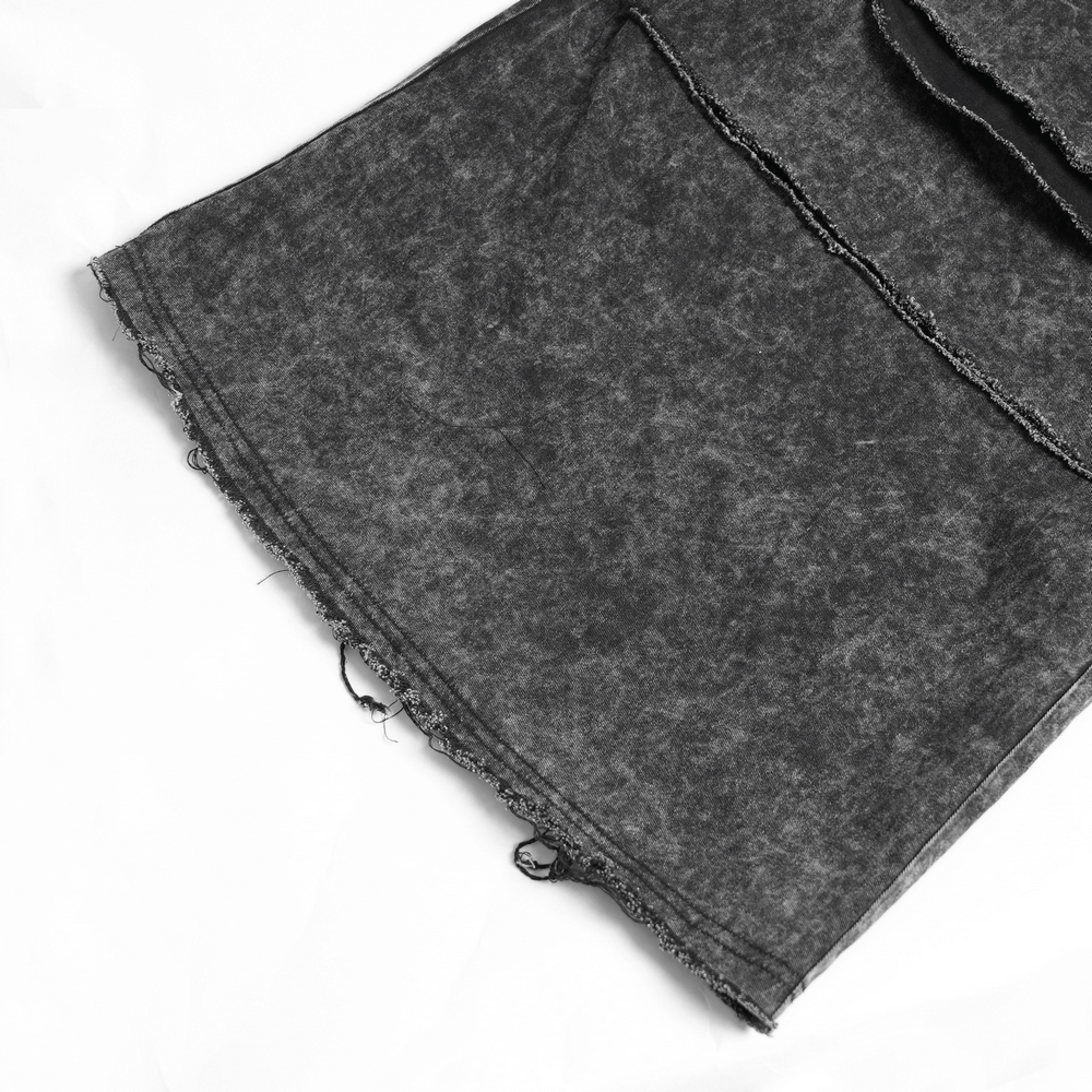 Close-up of distressed black pants with frayed edges and ripped details, showcasing punk style and edgy fashion.