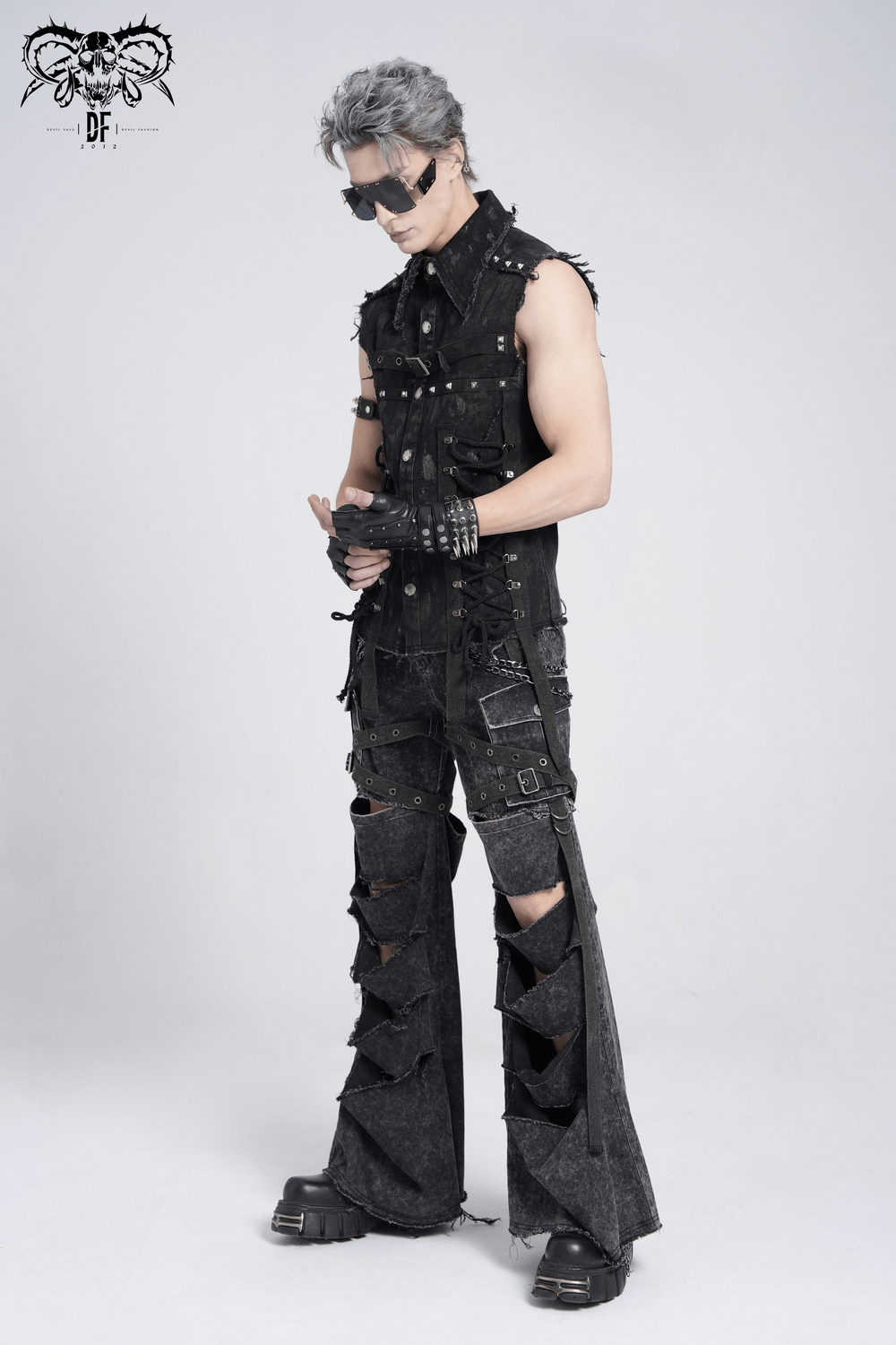 Male model wearing distressed punk flare pants with chains and buckle details in a dark streetwear style.