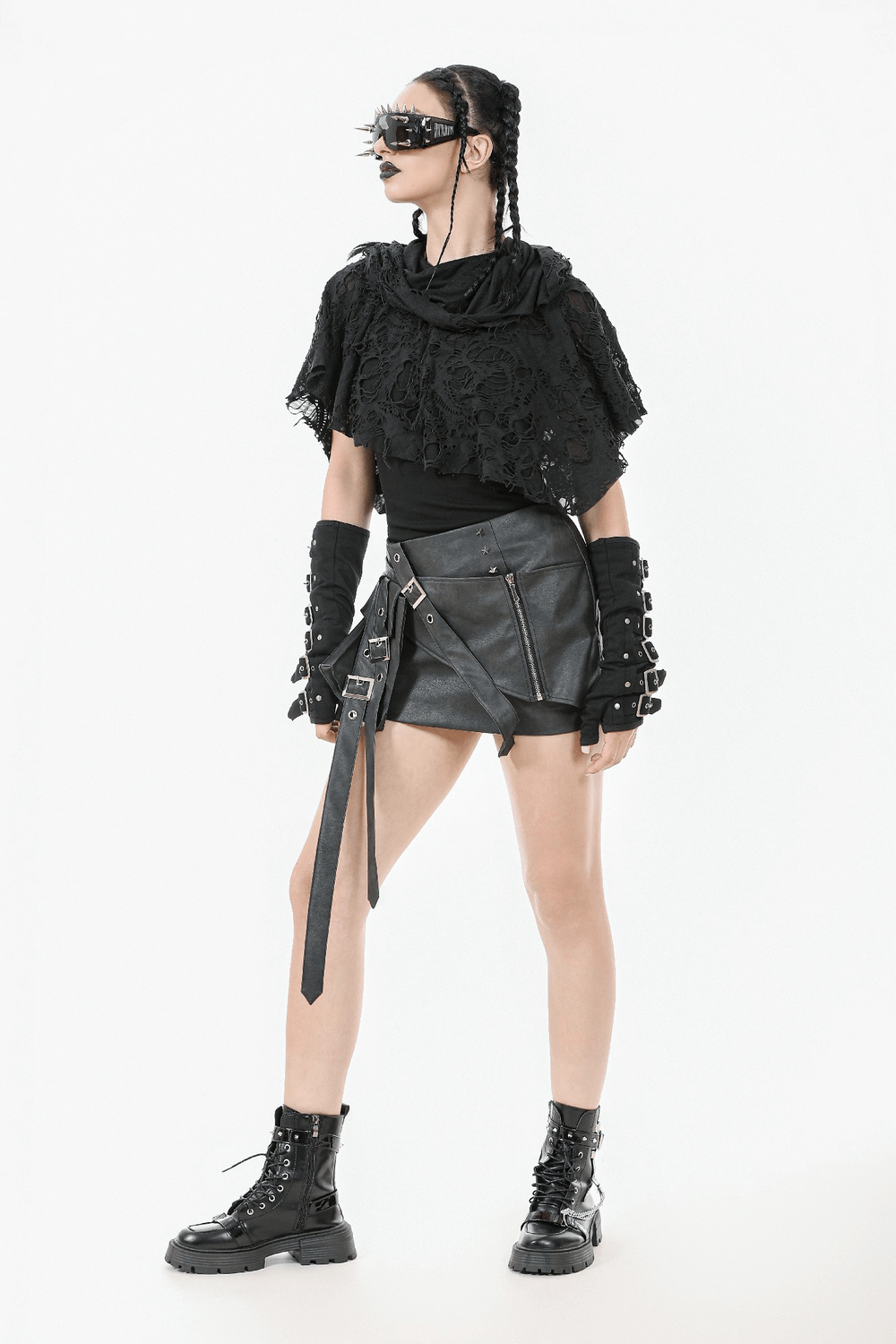 Fashionable woman in distressed punk hooded poncho cape, styled with edgy black mini skirt and accessories, perfect for a bold look.