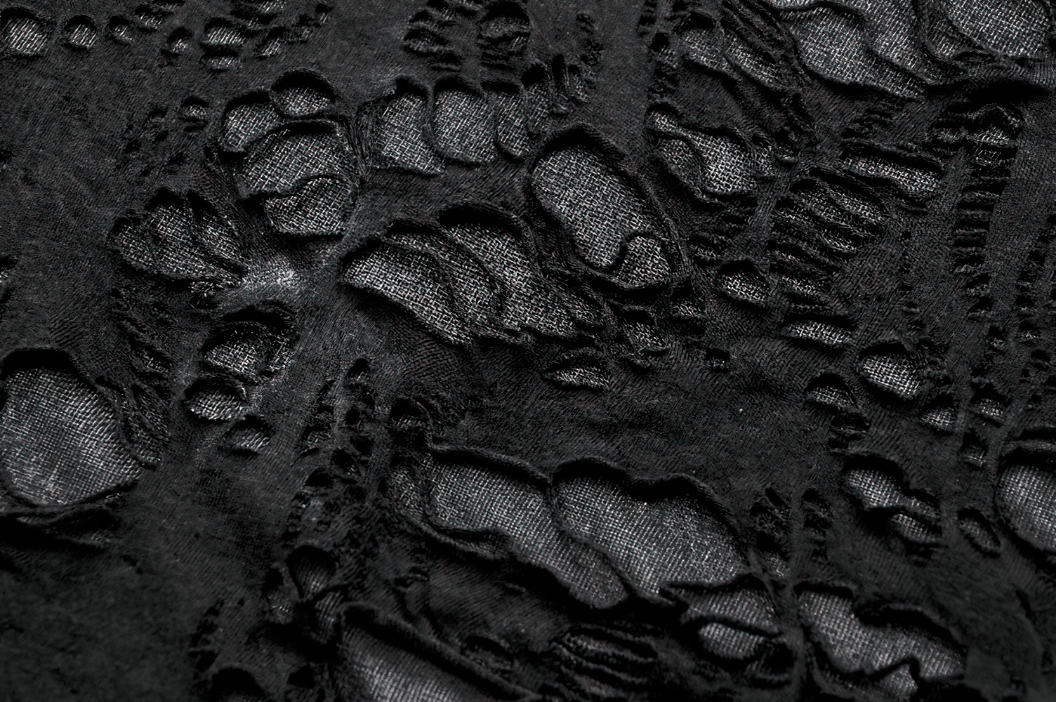 Close-up of distressed black fabric with tattered design, perfect for a punk hooded poncho cape.