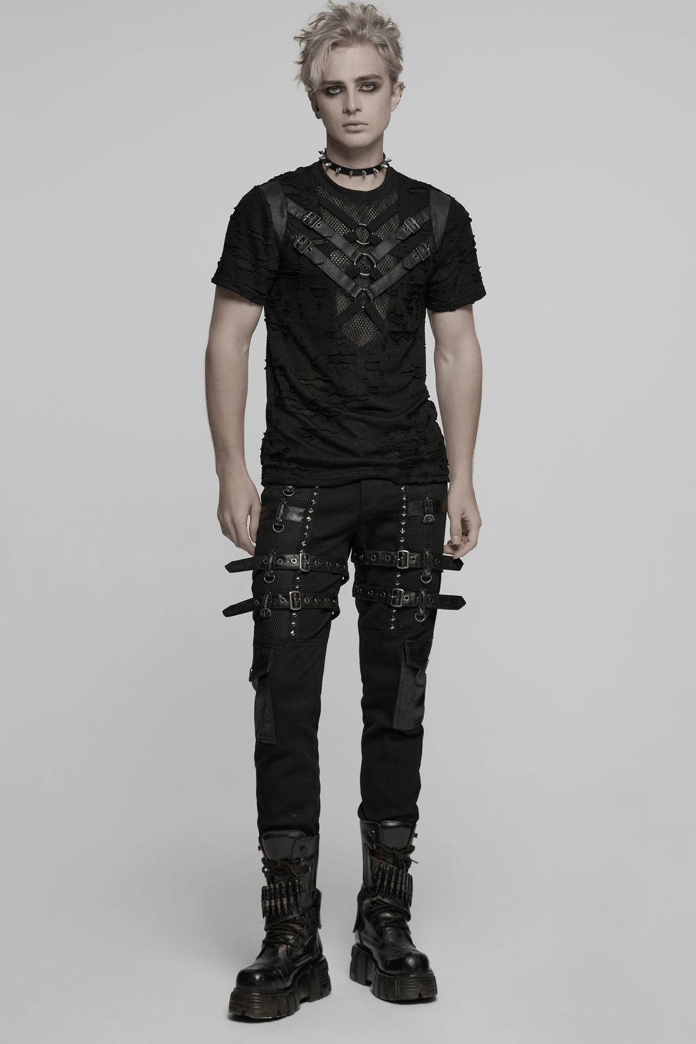 Edgy male model in distressed punk mesh t-shirt with leather straps and rings, showcasing a rebellious style.