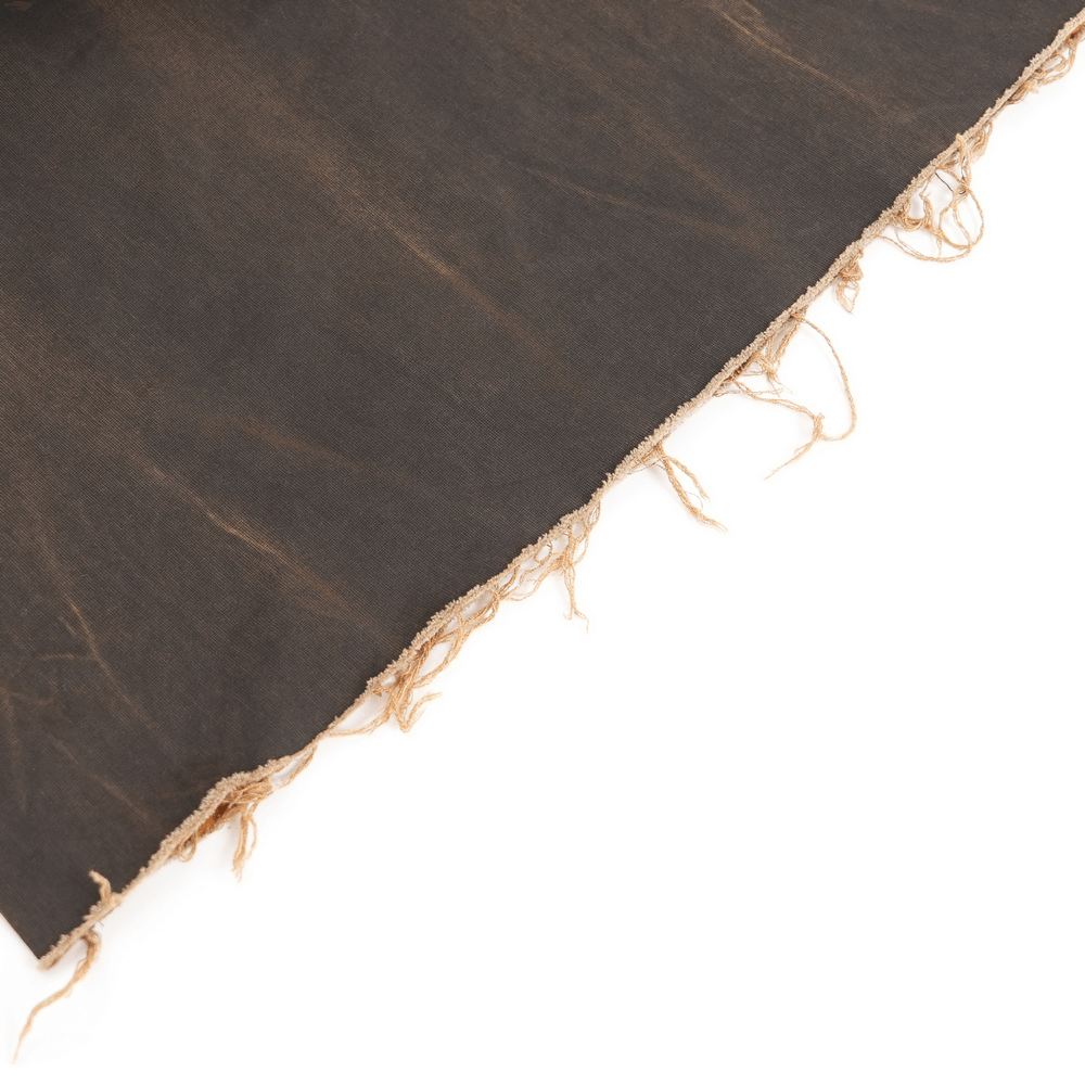 close-up of tiered raw hem detailing on distressed wide leg pants with a dark wash background