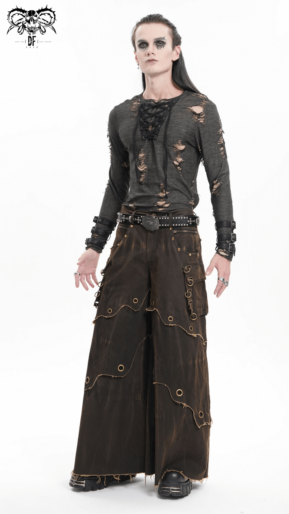 Male model wearing distressed wide-leg pants with grommets and raw hem, paired with a ripped long-sleeve top.