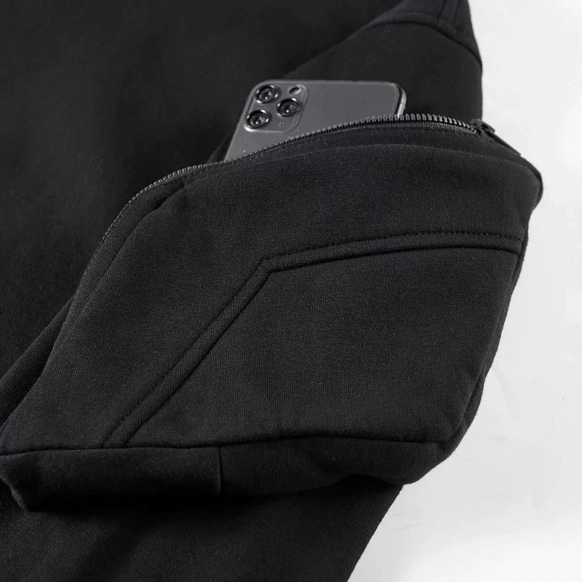 Close-up of a black hoodie sleeve pocket holding a smartphone, showcasing stylish and practical alternative fashion.