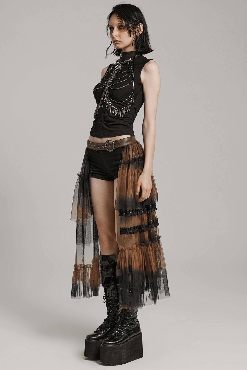 Model showcasing a dramatic long layered mesh half skirt with a belt, styled for a bold and edgy look.