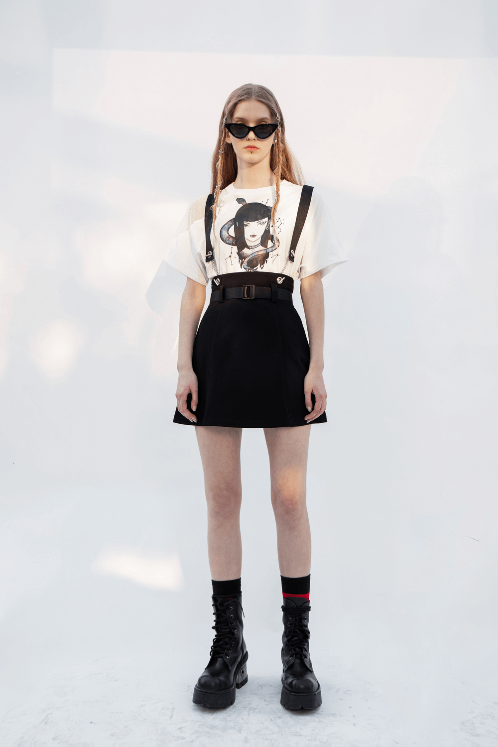 Chic model in Edgy A-Line Mini Skirt with detachable chain straps, styled with a graphic tee and combat boots.