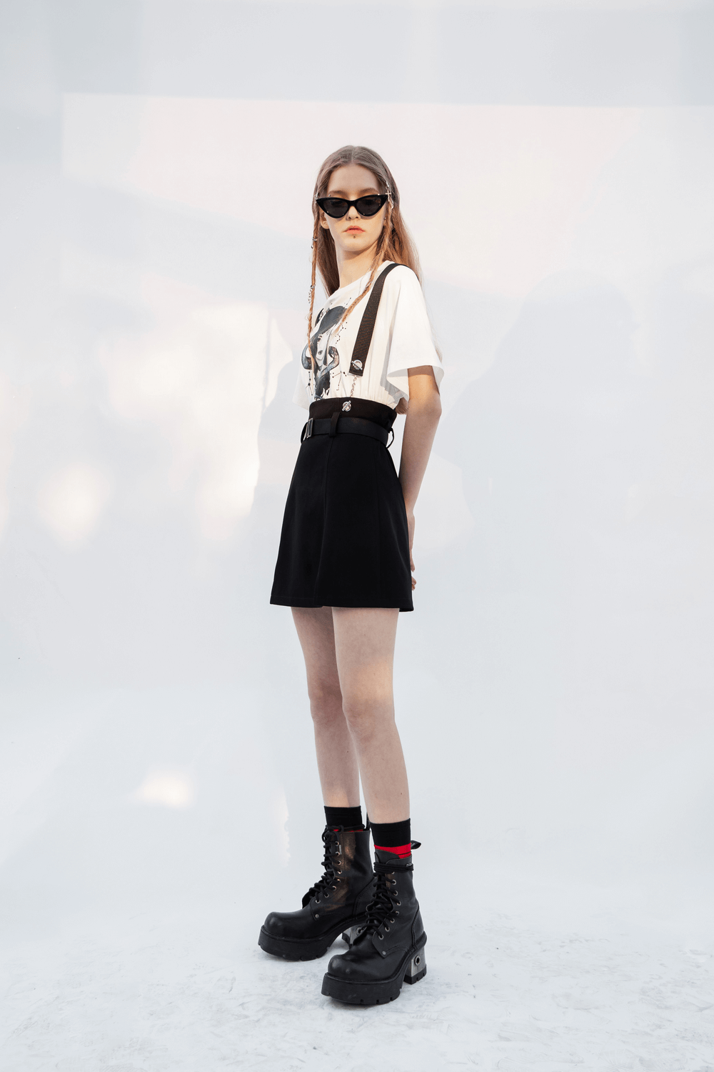 Edgy girl fashion featuring A-line mini skirt with chain straps, paired with a graphic tee and chunky boots.