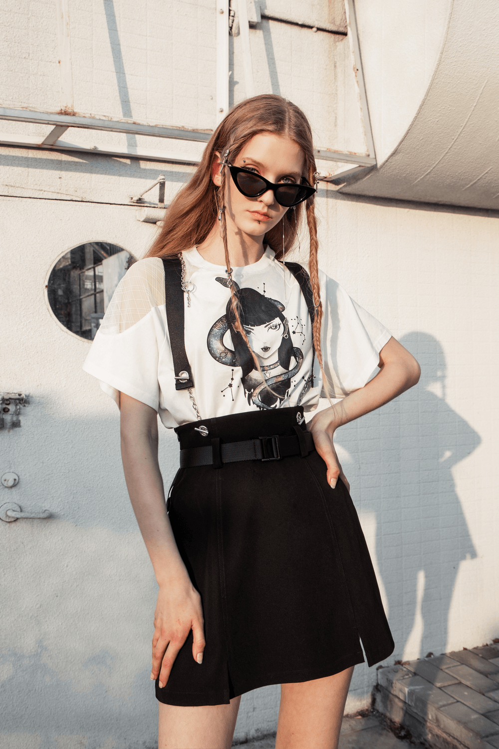 Chic model in A-line mini skirt with detachable chain straps and stylish graphic tee in urban setting.