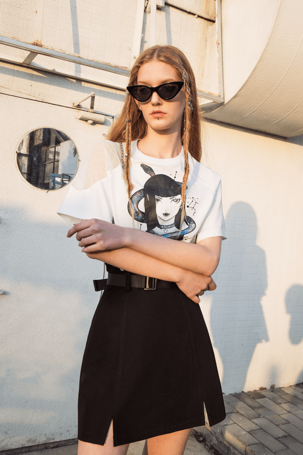 Model showcasing an edgy A-line mini skirt with detachable chain straps and a graphic tee.