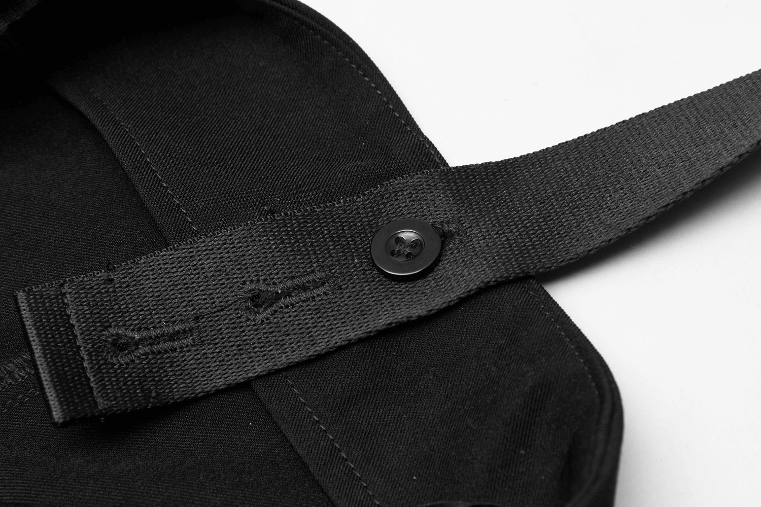 Close-up of detachable chain strap featuring a button on an edgy A-line mini skirt, showcasing its unique design.