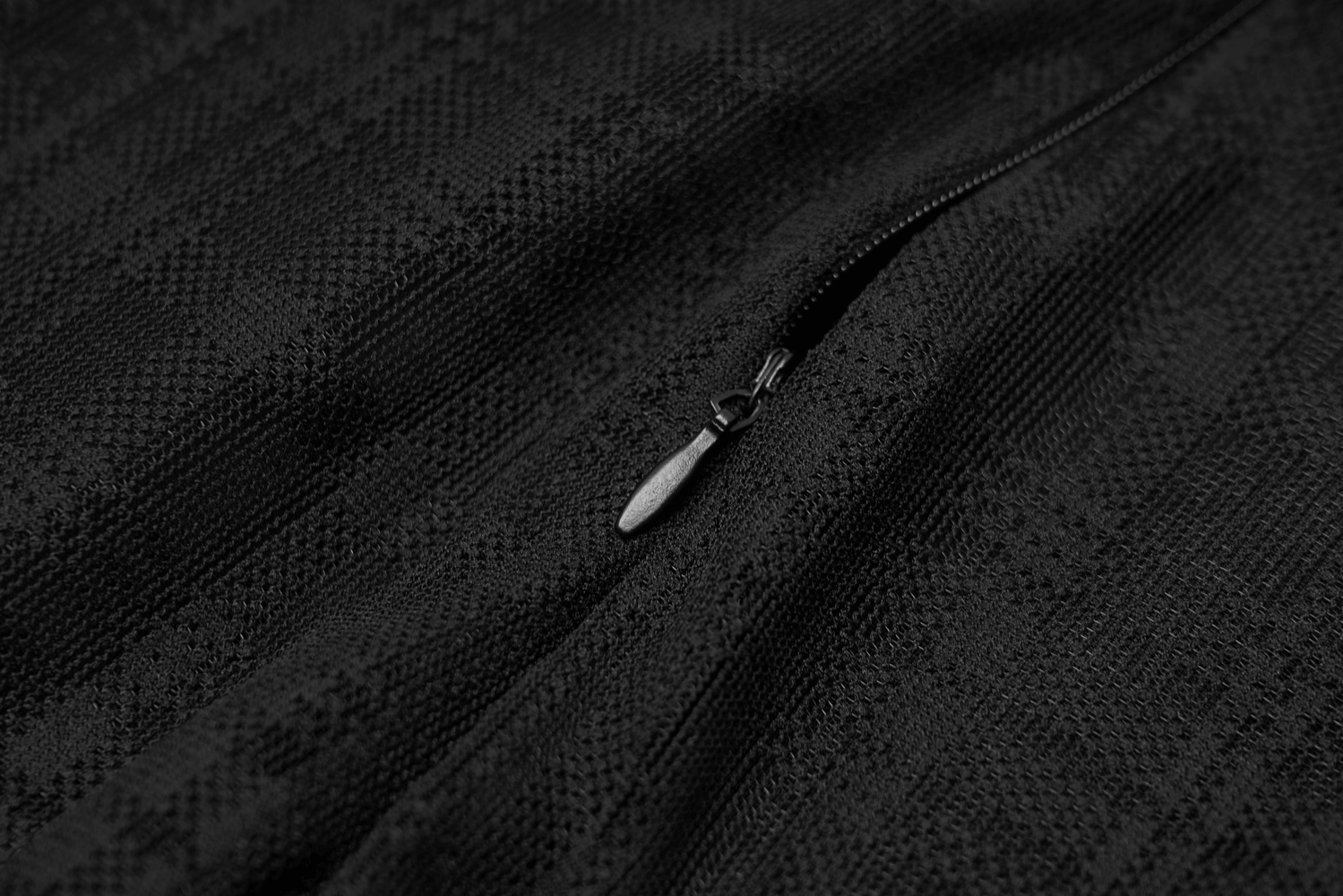 Close-up of a black textured fabric with a zipper, perfect for edgy fashion styles.