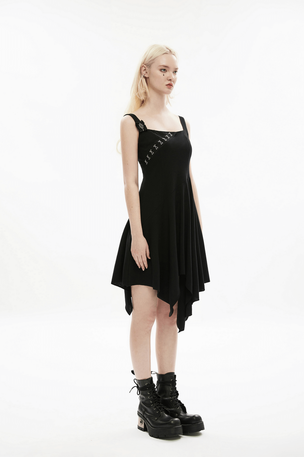 Edgy asymmetrical black slip dress with brooch detail, featuring a unique square hemline and metal embellishments.