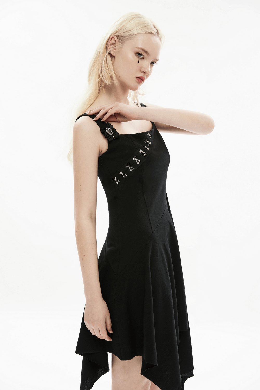 Edgy asymmetrical black dress with brooch detail and unique hemline, perfect for a chic statement look.