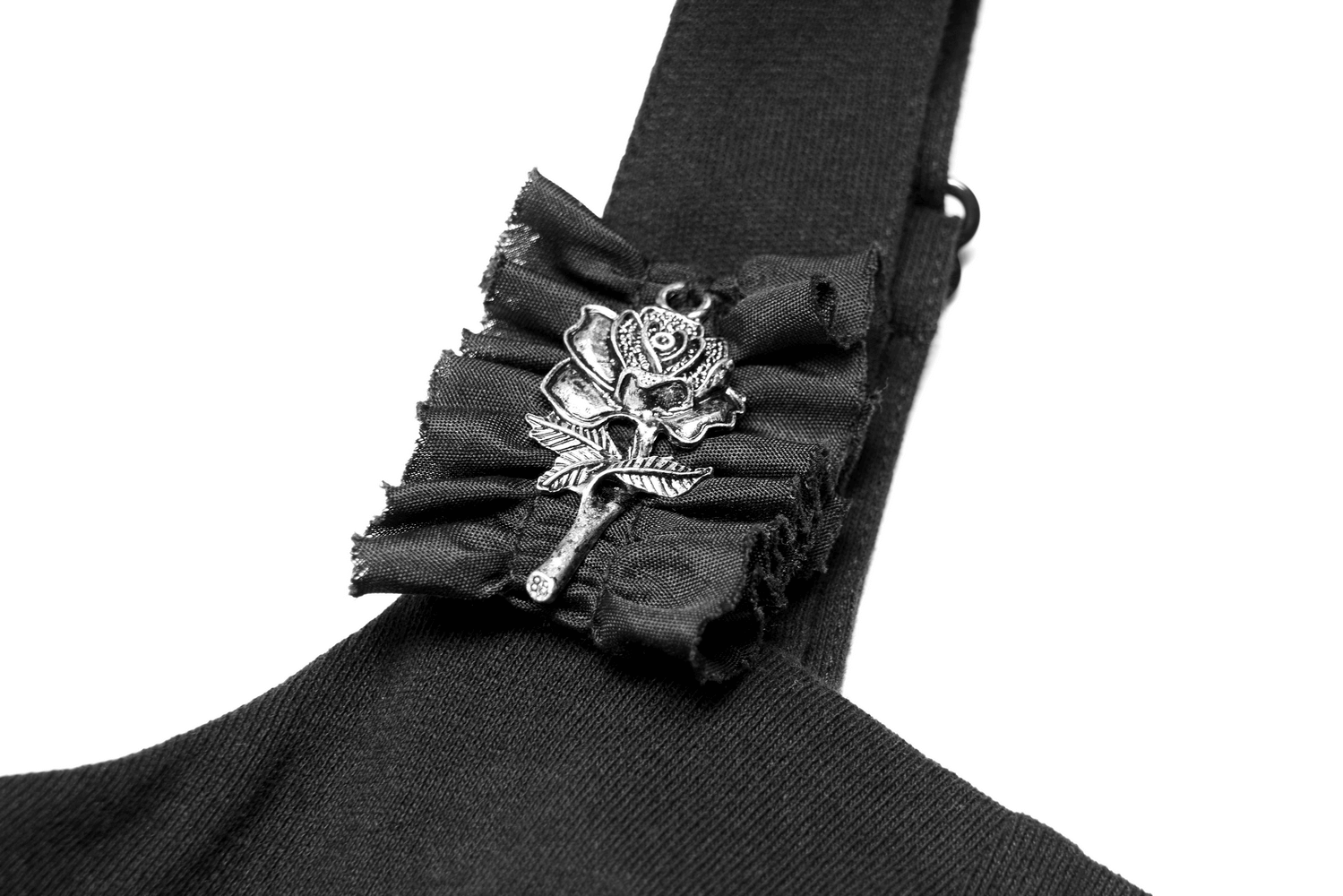 Close-up of a black dress strap featuring a detachable rose medal brooch with ruffled fabric detail.