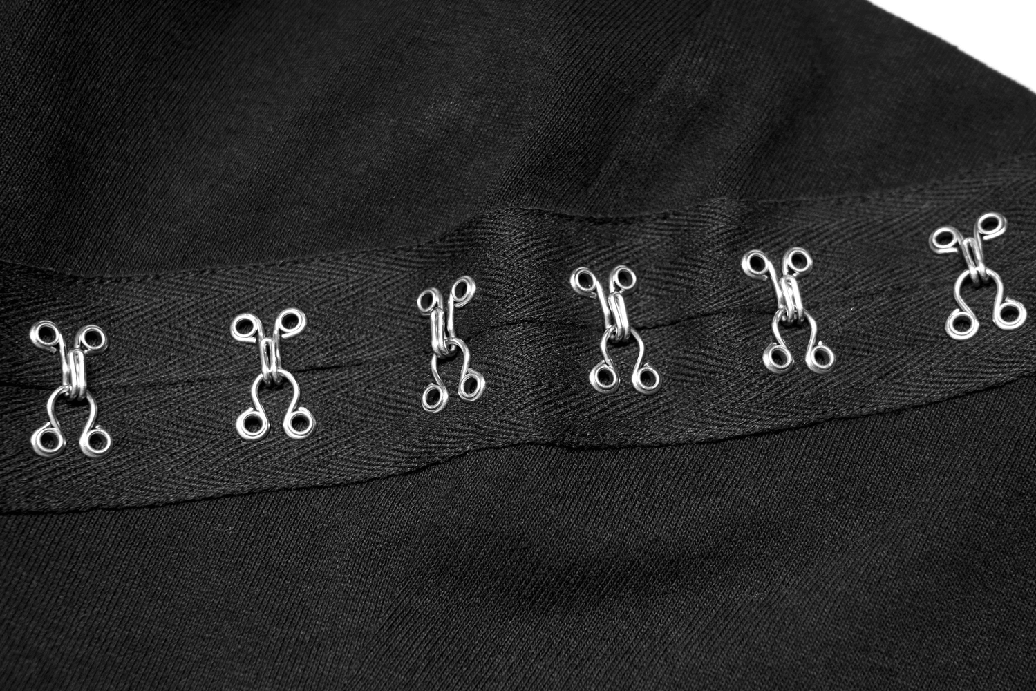 Close-up of metal hook and buckle embellishments on a black dress, showcasing edgy and avant-garde design.