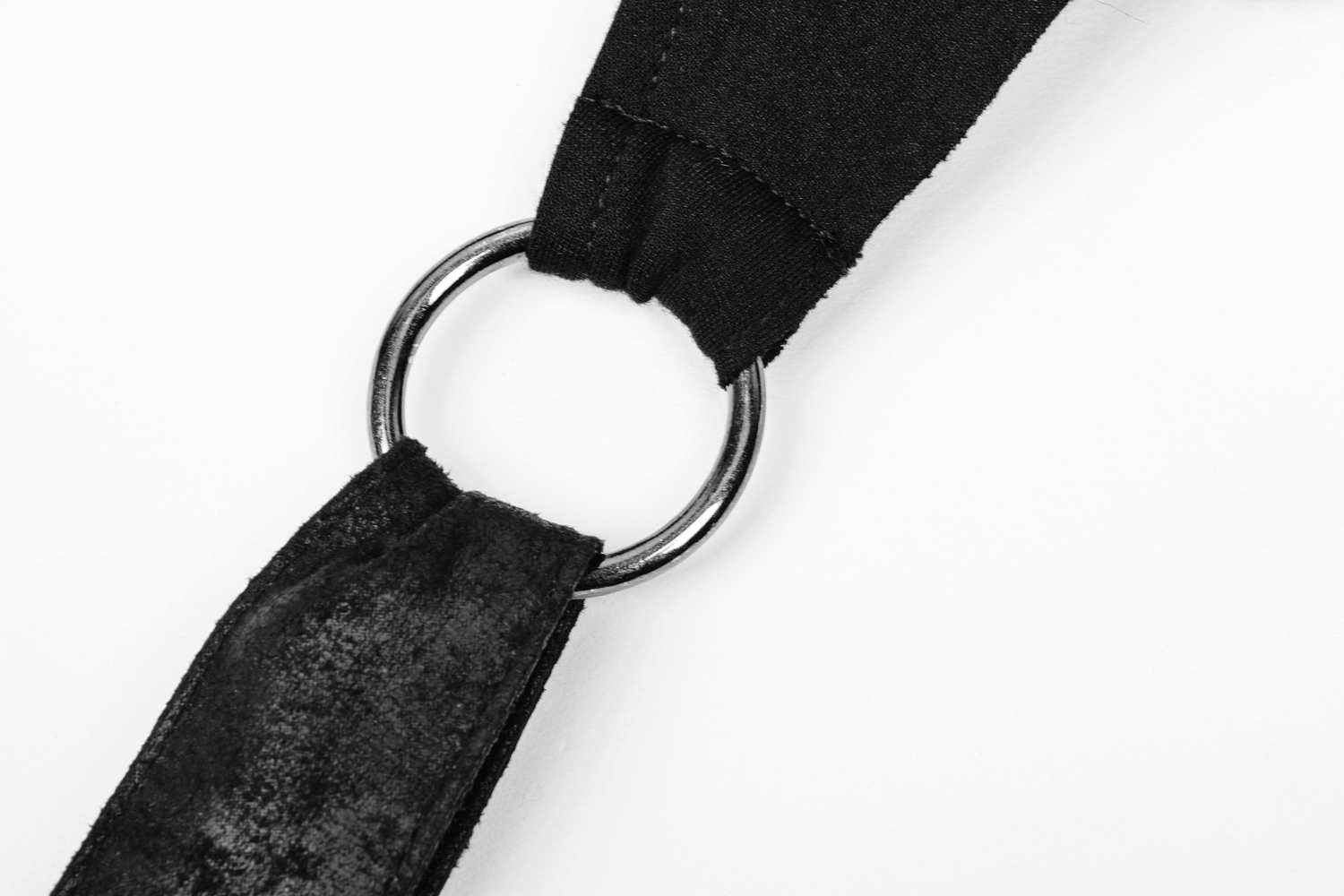 Close-up of a black fabric strap with a metal ring, showcasing gothic-inspired design details.