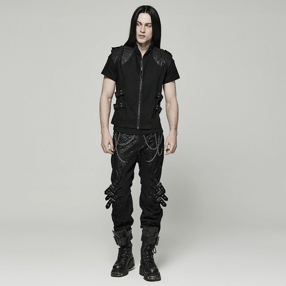 Stylish person in a black punk vest with buckles and dark pants, showcasing edgy gothic fashion.