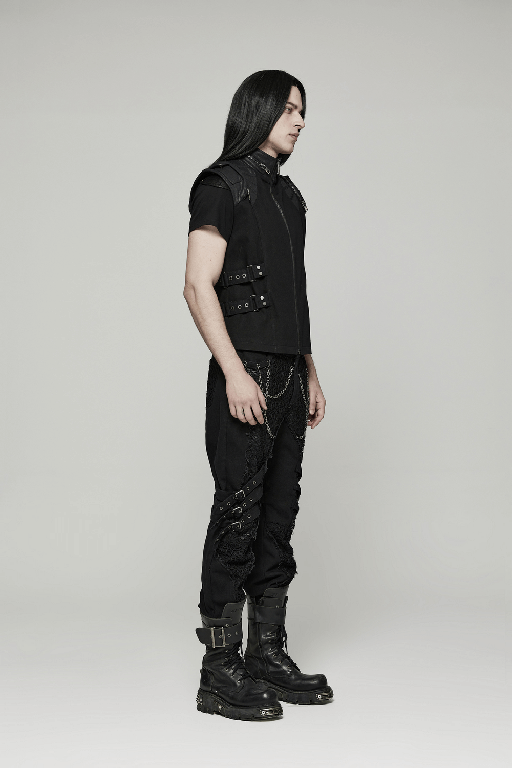 Stylish model in an edgy black buckle-up gothic vest, showcasing punk fashion and attitude with sleek boots.
