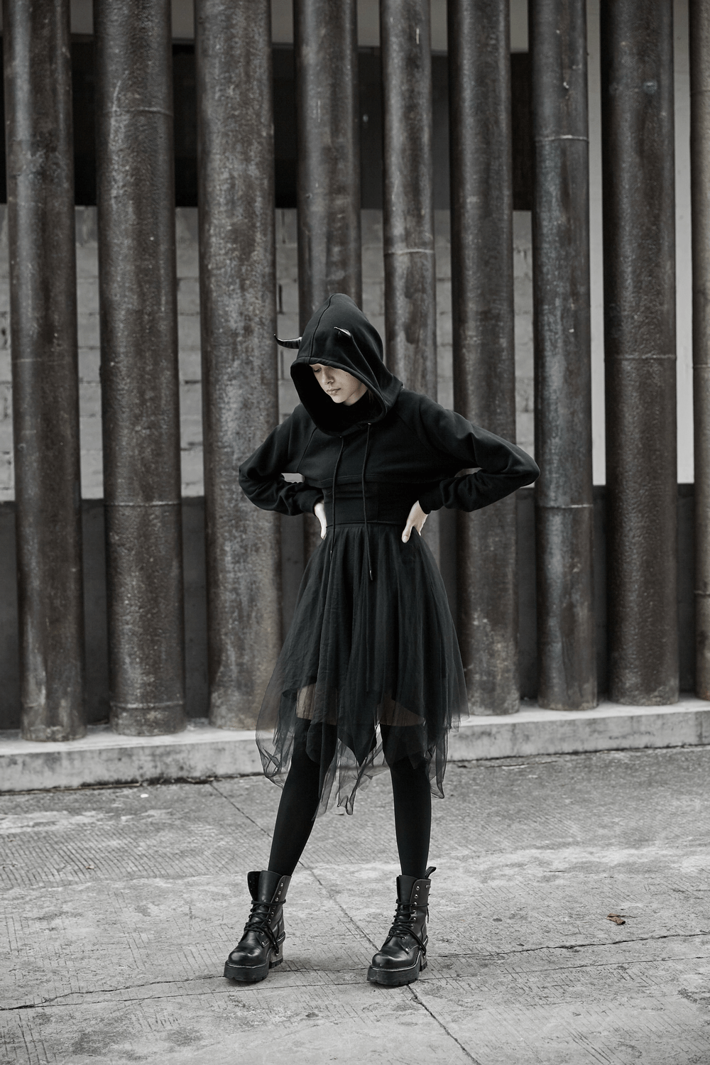 Edgy black crop hoodie with devil horns, paired with a tulle skirt and combat boots in an urban setting.