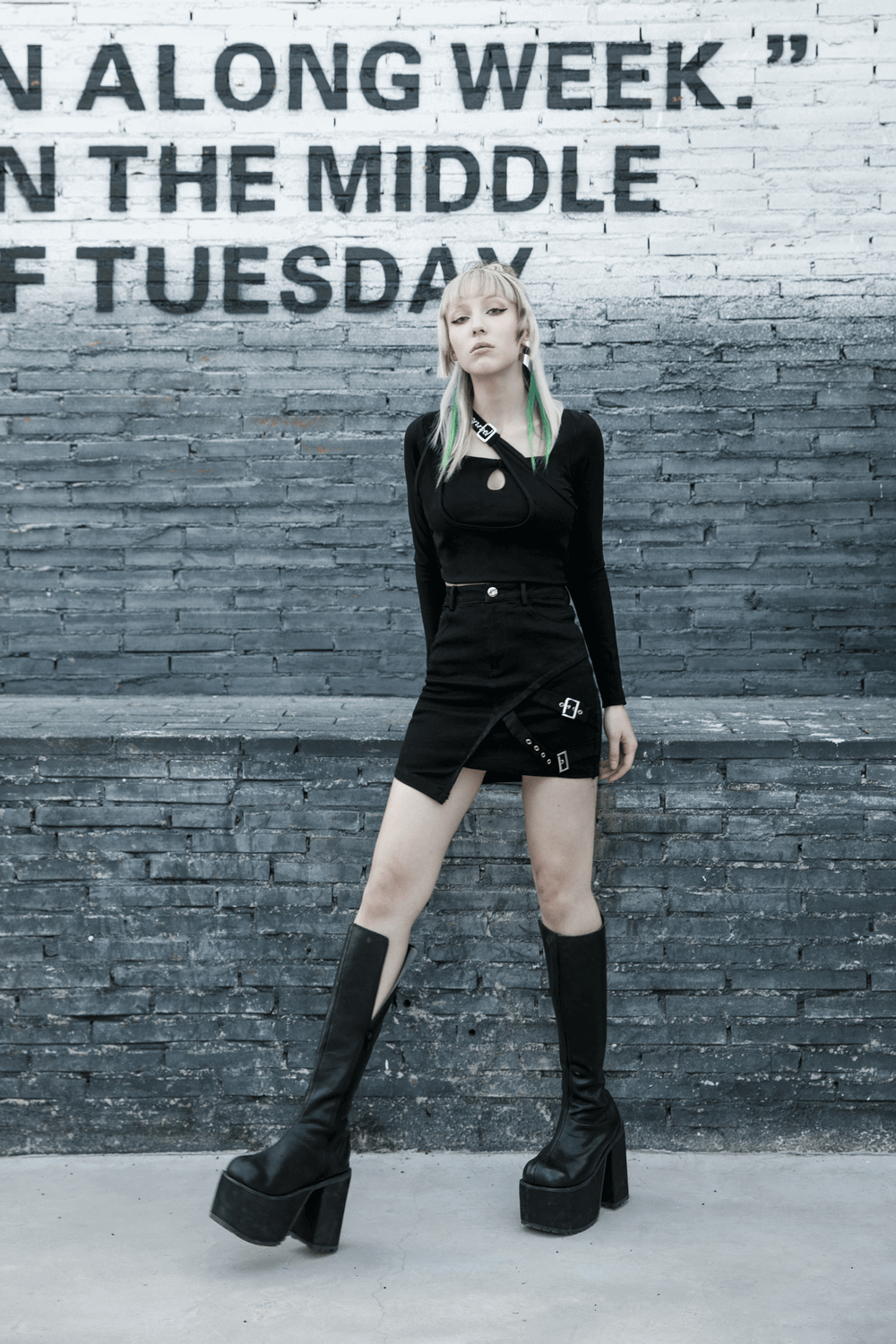 Edgy black denim mini skirt with buckle detail, styled with platform boots against an urban backdrop.