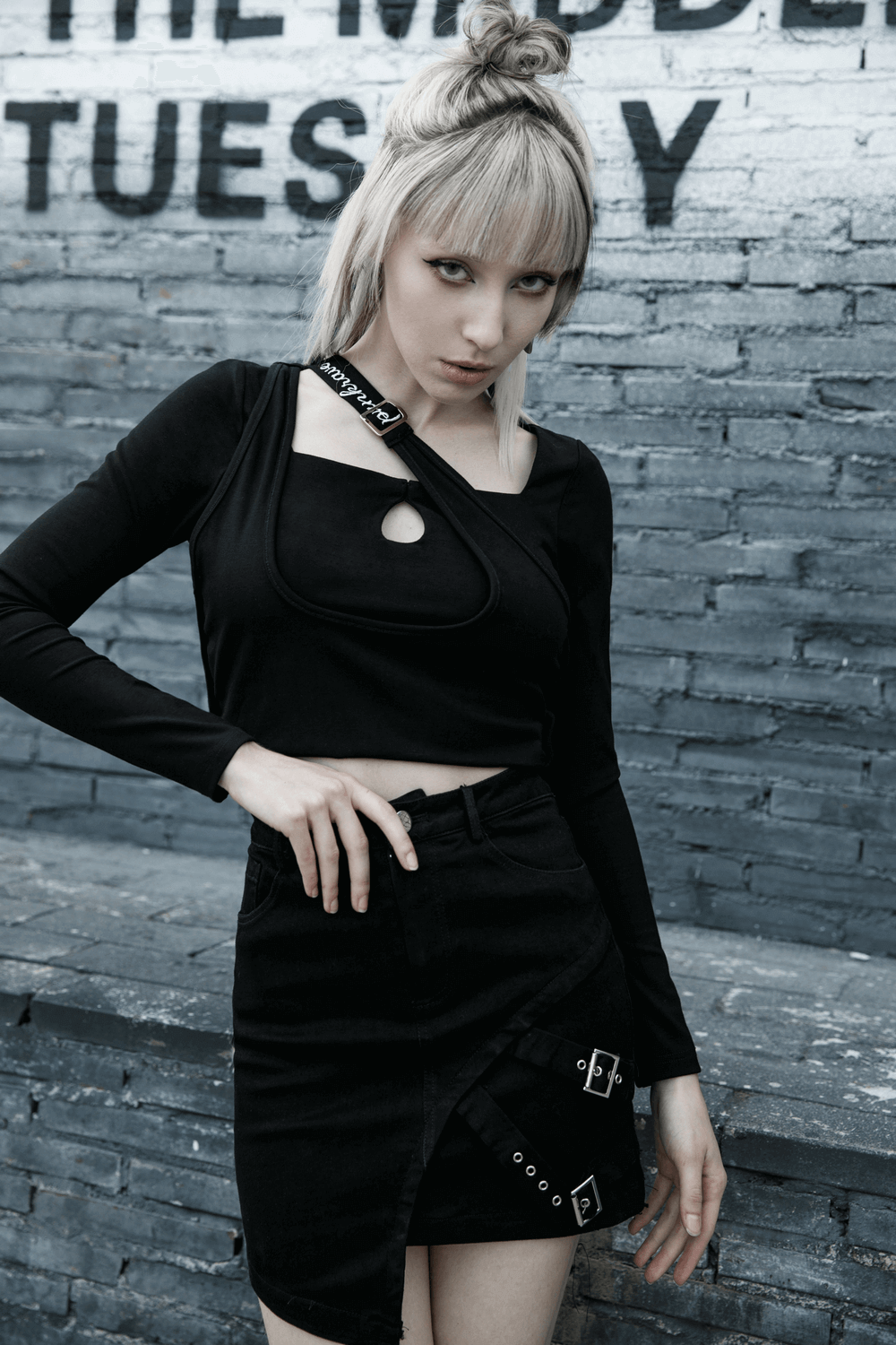 Edgy black denim mini skirt with buckle detail, paired with a stylish black top against a textured backdrop.