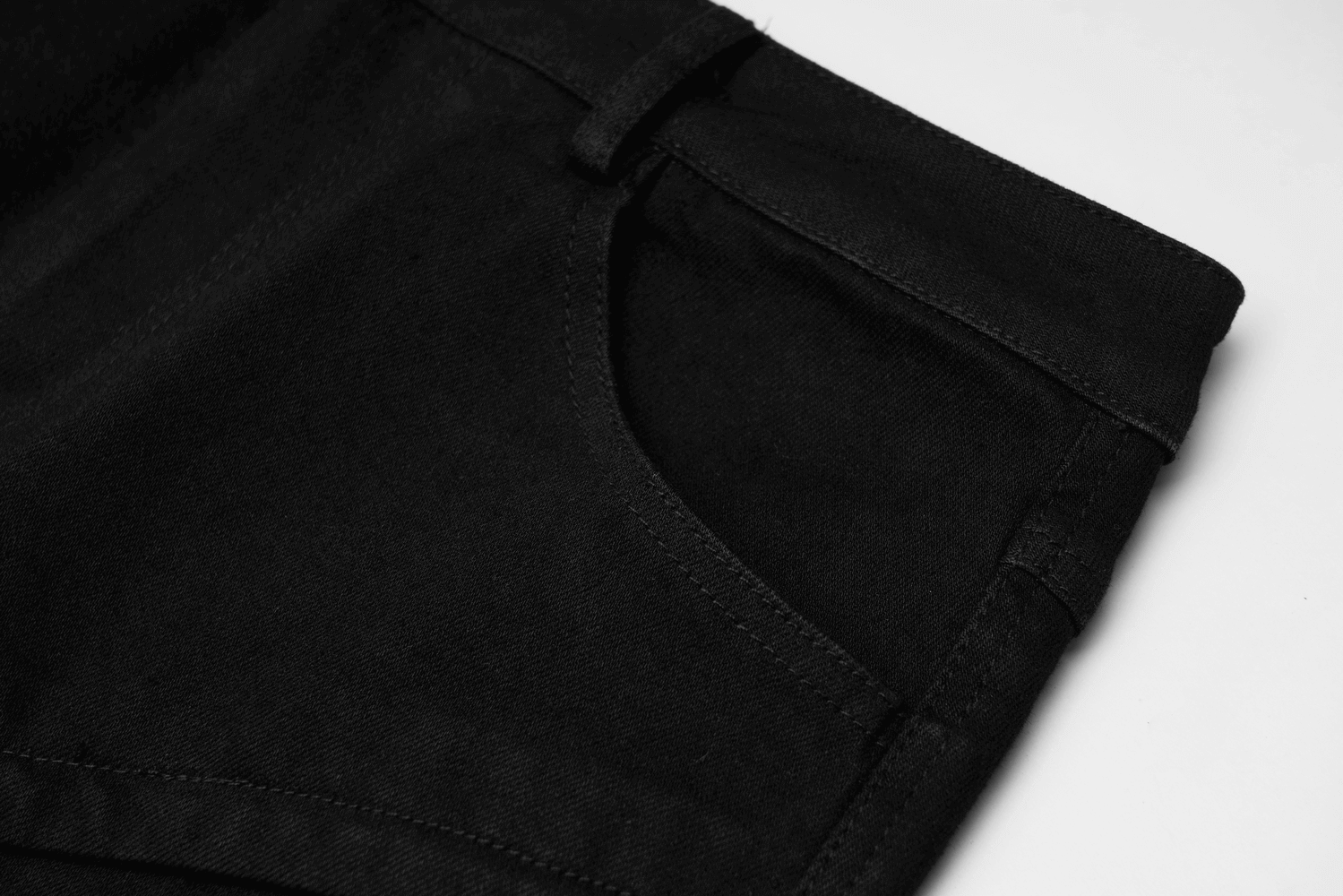 Close-up of edgy black denim mini skirt showcasing pocket detail and buckle strap features.