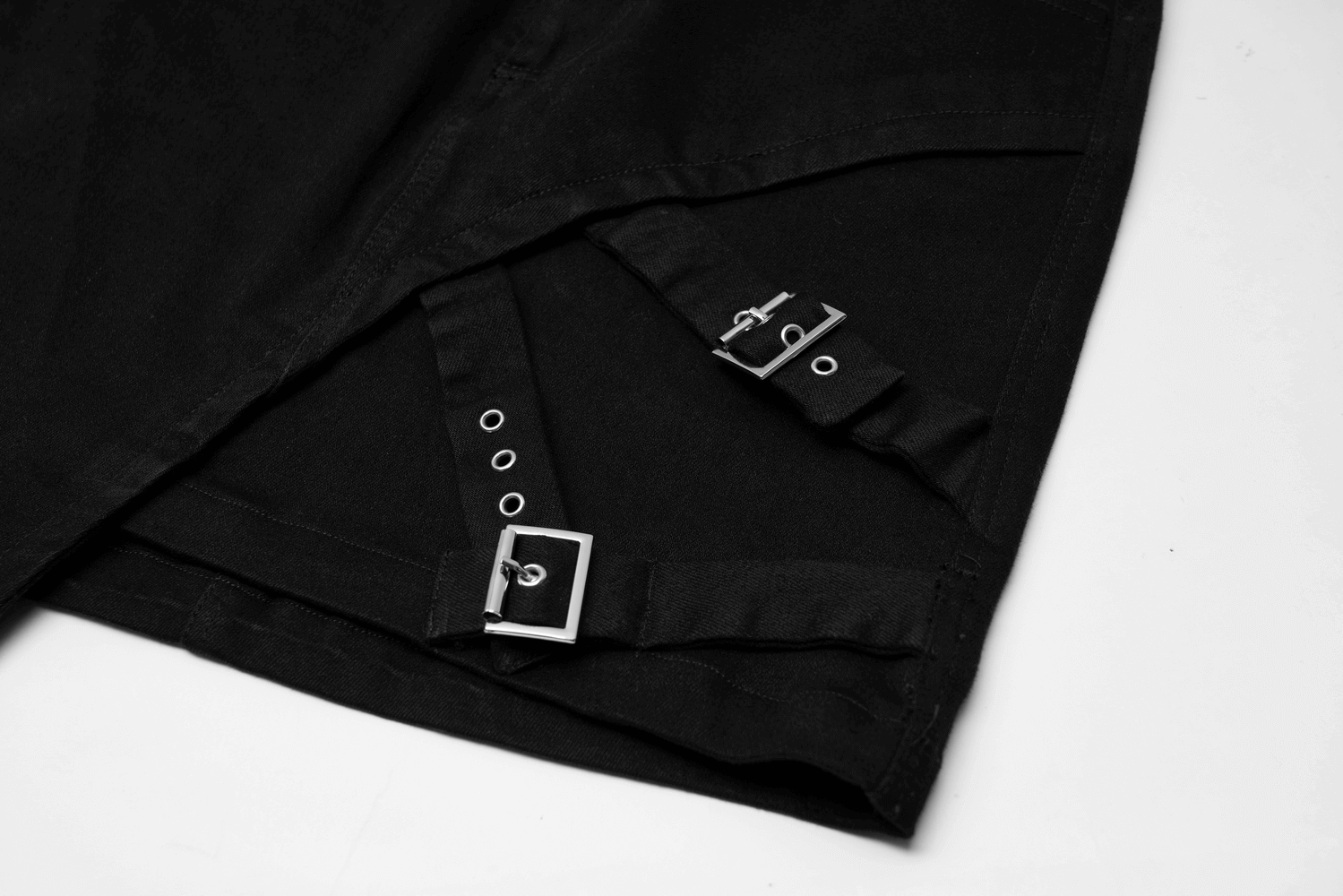 Close-up of edgy black denim mini skirt showcasing buckle details and asymmetric design.