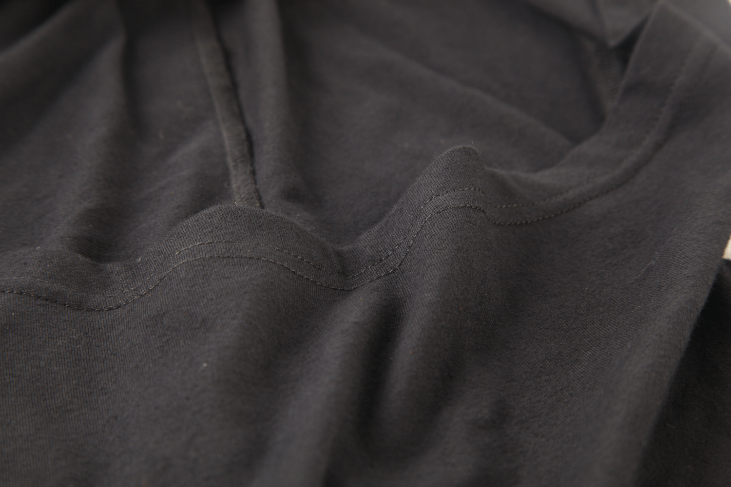 Close-up of black fabric showcasing the soft texture and detailed stitching of an edgy hooded top.