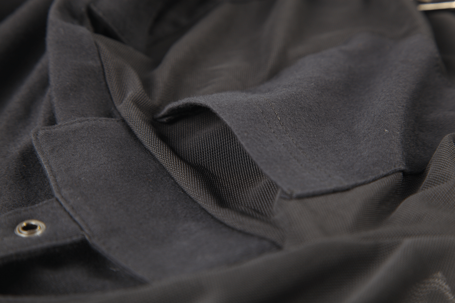 Close-up of black hooded top showcasing mesh sleeves and unique corset detailing.