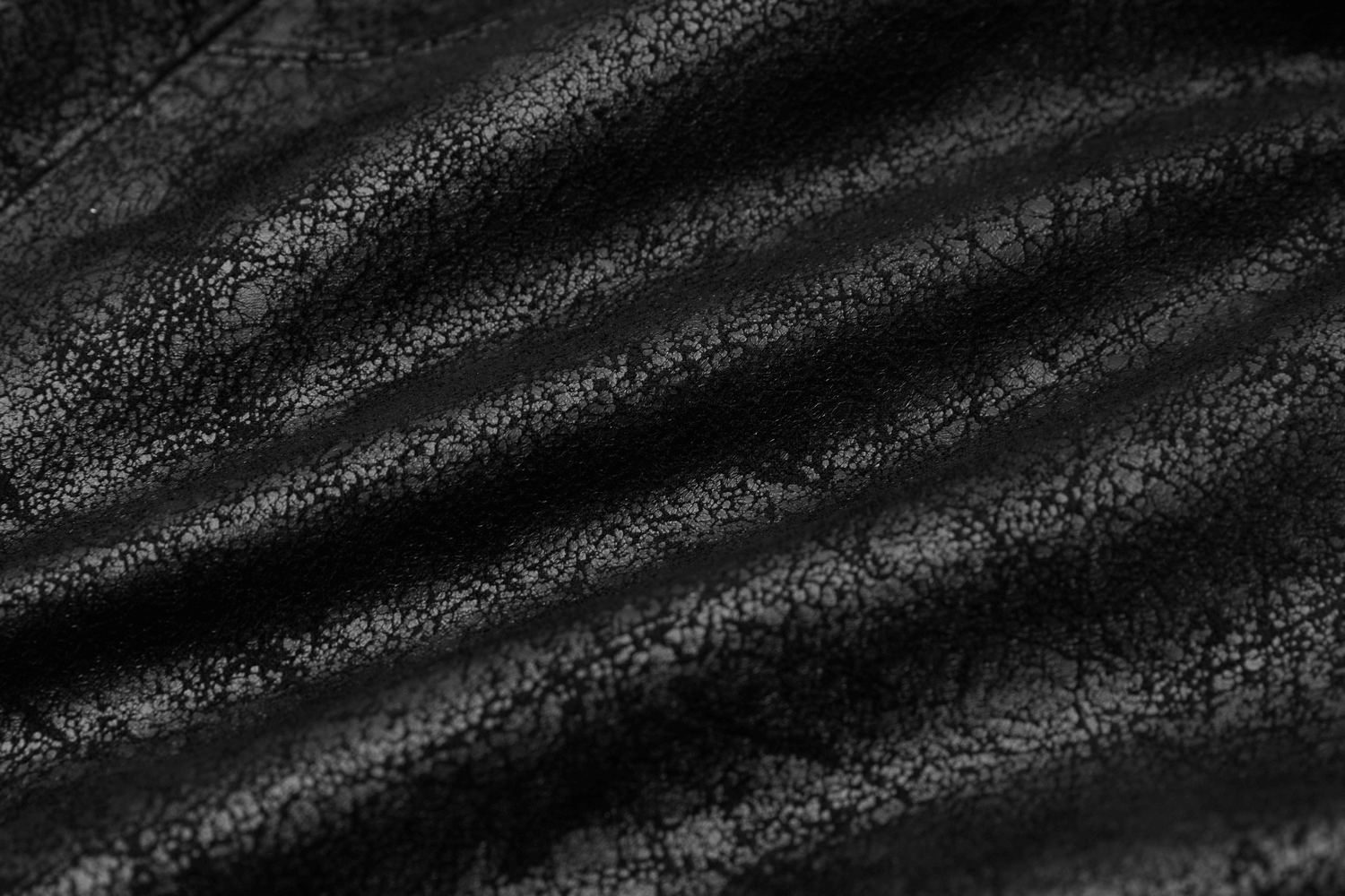 Close-up of textured black leather with unique creases and patterns, showcasing its edgy style.