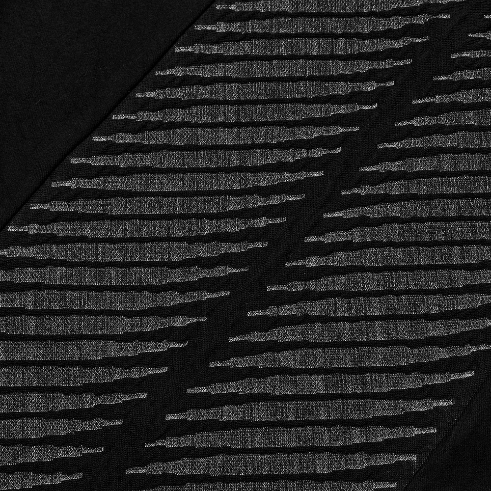 Close-up of edgy black spliced top featuring unique 3D jacquard design and textured knit fabric.