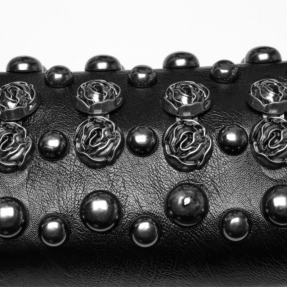 Close-up of edgy black bag adorned with gothic rose rivets and metal studs, showcasing its bold design details.