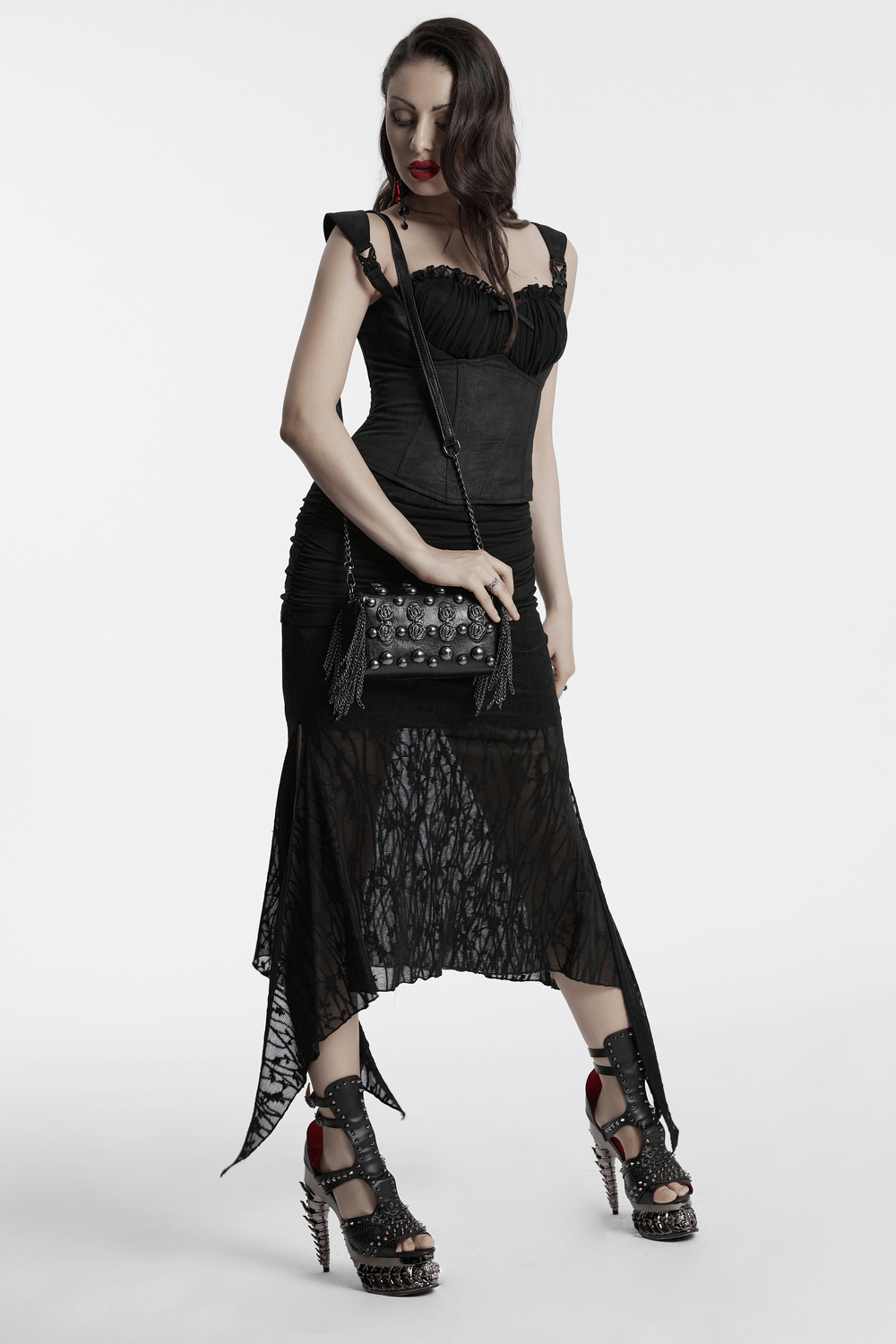 Stylish model wearing an edgy black dress and spiked heels, holding a studded crossbody bag with gothic rose rivets.