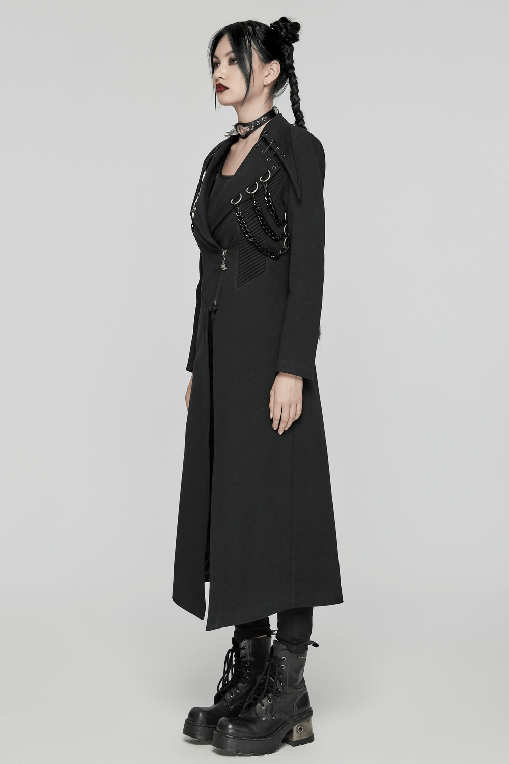 Edgy black trench coat with D-buckles and chains, styled for a punk-inspired silhouette.
