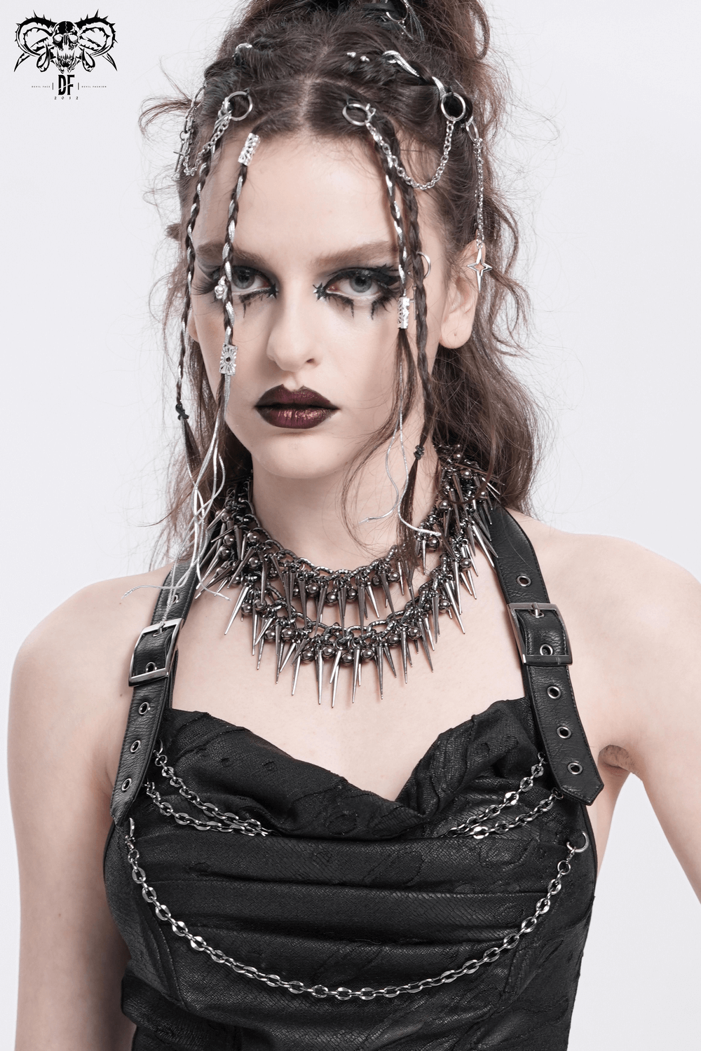 Edgy woman showcasing a statement choker with chains and spikes, styled with bold makeup and intricate hair accessories.