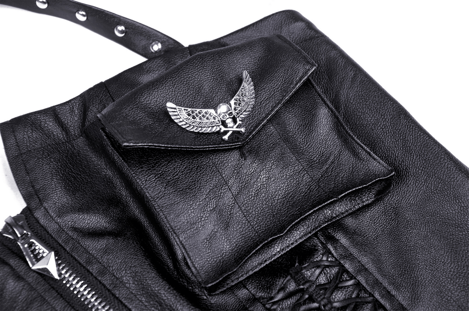 Close-up of black faux leather dress featuring a skull and wings metal accent on a pocket.