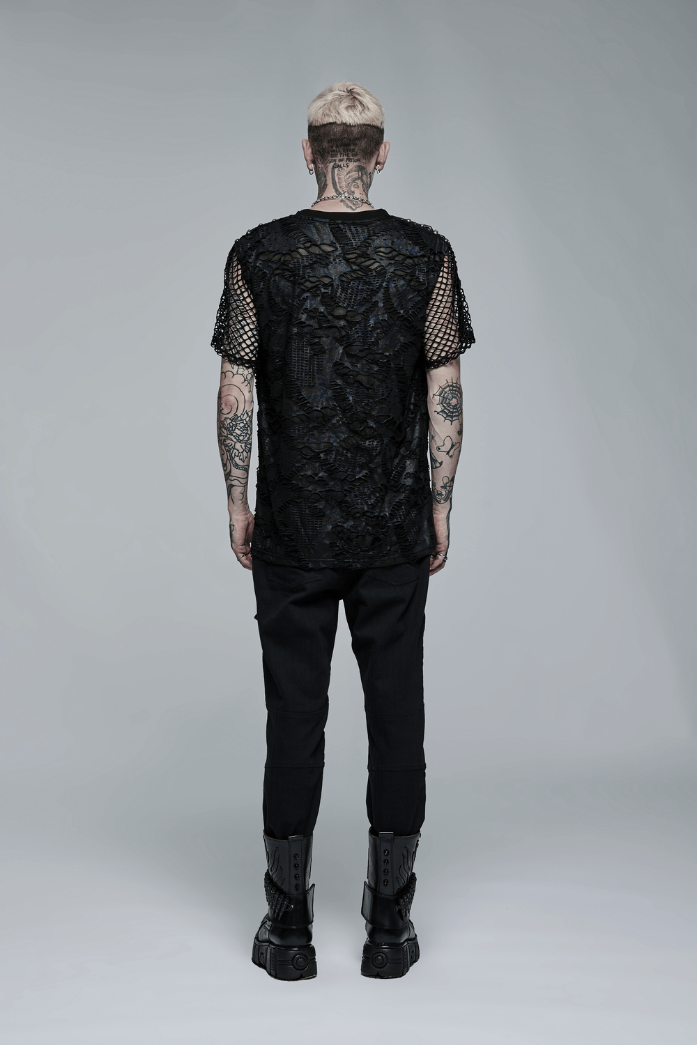 Back view of a man in a gothic mesh layered tee with tattoos, showcasing edgy urban fashion and mesh details.