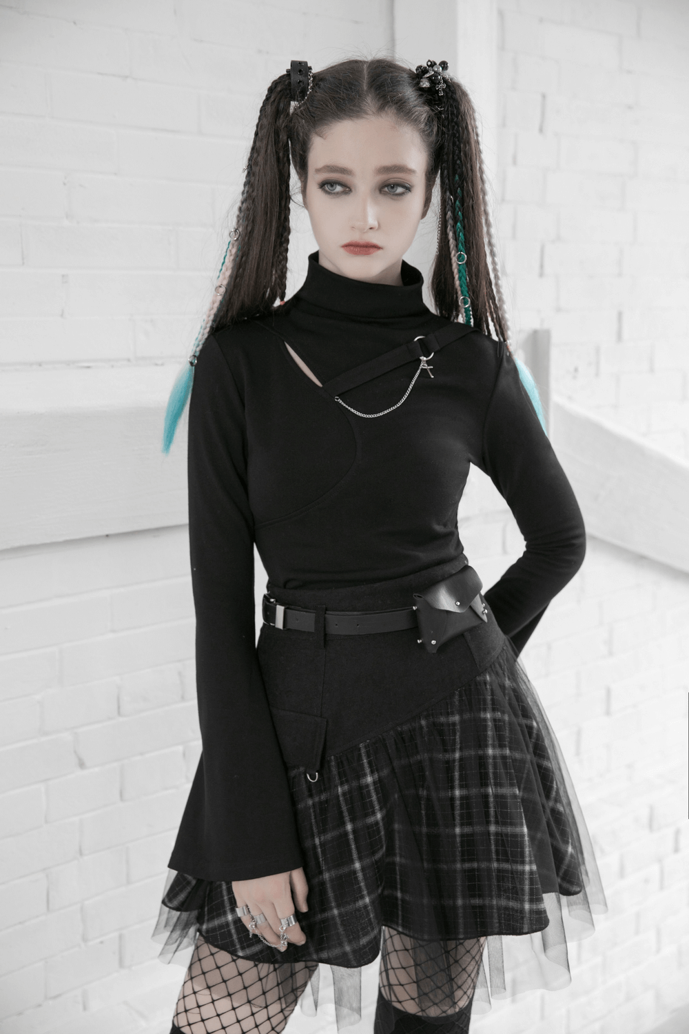 Edgy model in high-waisted black skirt with plaid and tulle, showcasing punk style with unique accessories.