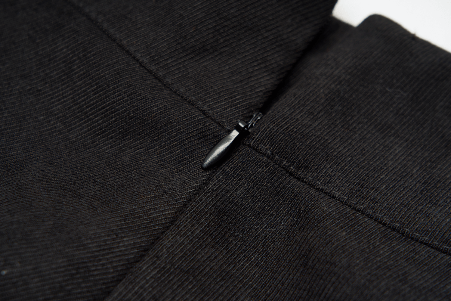 Close-up of zipper detail on an edgy high-waist black skirt showcasing textured fabric.