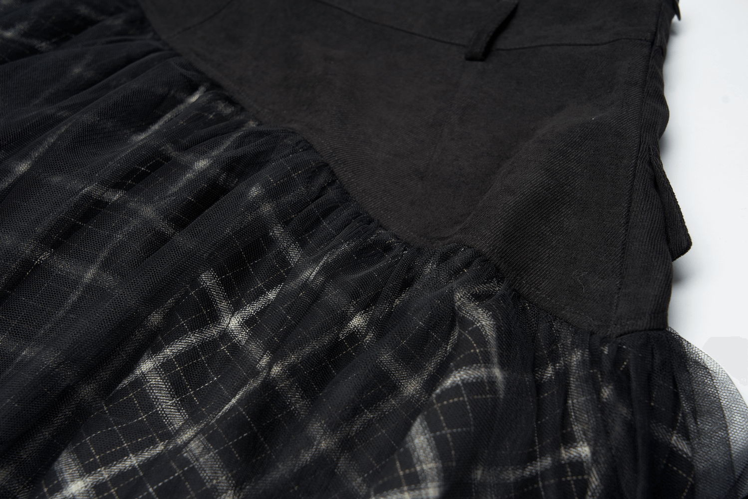 Close-up of an edgy high-waist plaid and tulle punk mini skirt showcasing black plaid and dramatic mesh layers.