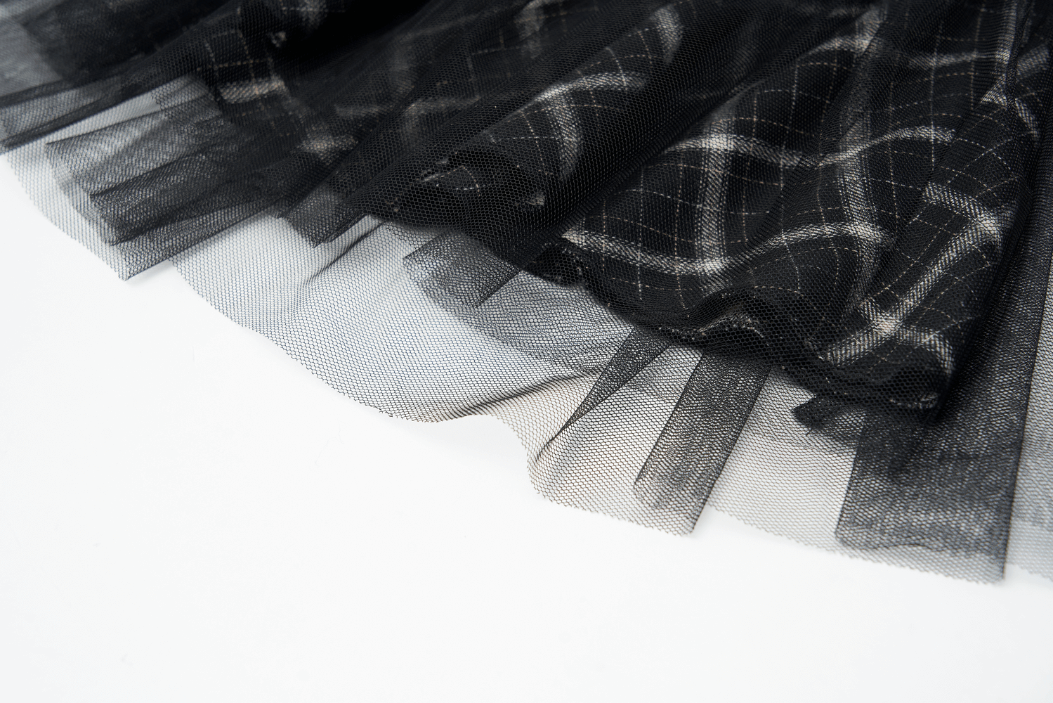 Close-up of the layered black plaid and tulle fabric of an edgy high-waisted punk mini skirt.